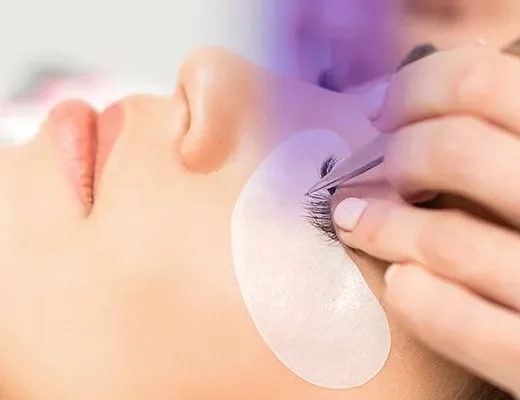 Technicienne appliquant des extensions de cils sur une cliente allongée