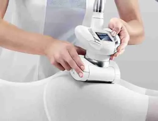 Technicienne utilisant un appareil esthétique sur la cuisse d’une cliente.